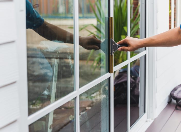 Worker use scraper cleaning window before installing tinting film